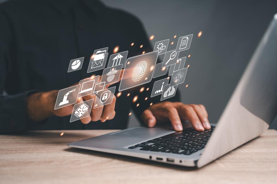 Photo d'une personne (visage non représenté) utilisant un ordinateur portable et pointant vers l'icône d'empreinte digitale. Il existe plusieurs autres icônes liées à la technologie entourant l’empreinte digitale. Concept technologique pour petites entreprises