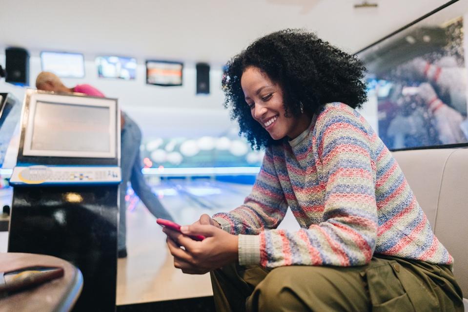 Young woman using the mobile phone at a bowling club