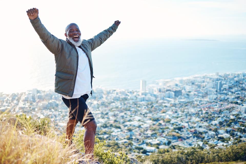 Portrait, black man on mountain and excited with exercise, celebration and view for fitness, happiness and hiking. Face, African American male athlete and mature gentleman with smile and training.