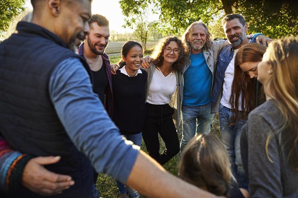Group of happy people embracing on a garden party at sunset