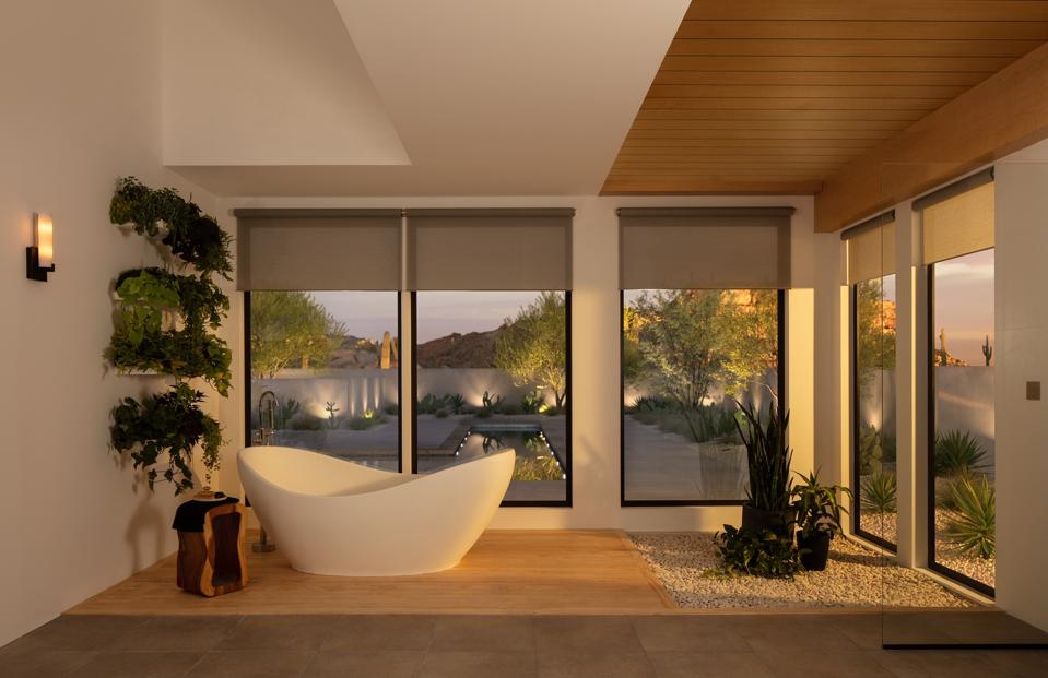 Bathroom with floor to ceiling windows, smart shades and an oval freestanding tub.