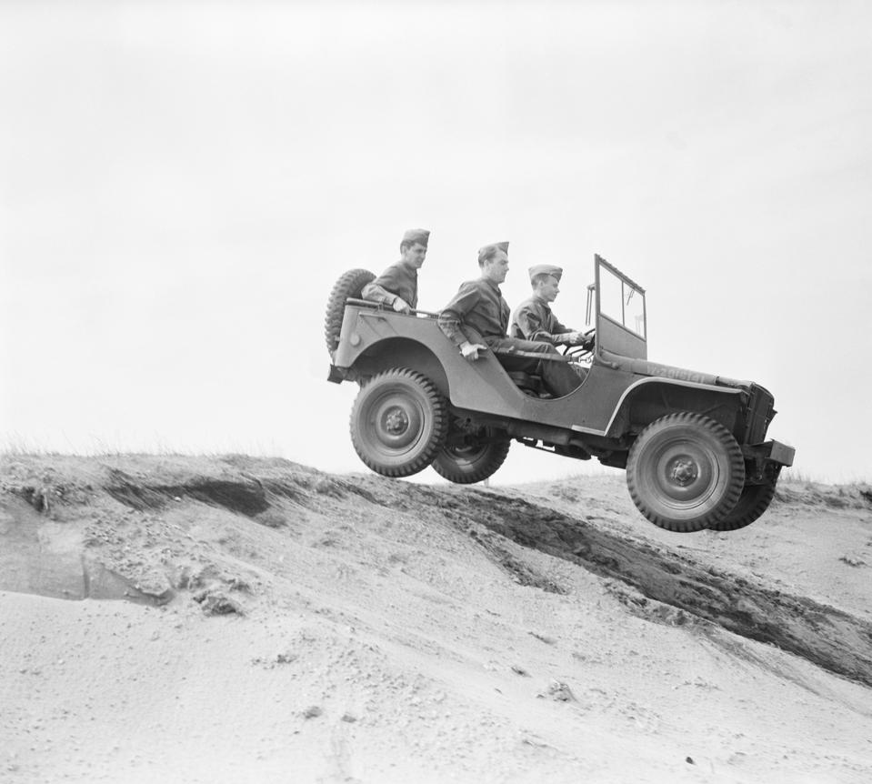 सैन्य कर्मी टीलों के नीचे जीप चला रहे हैं