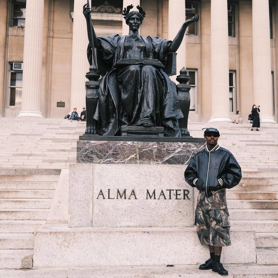 असाके 7 नवंबर, 2024 को एफ्रोडायस्पोरा कोलोक्वियम कार्यक्रम के उद्घाटन के बाद कोलंबिया विश्वविद्यालय के मॉर्निंगसाइड हाइट्स परिसर में अल्मा मेटर प्रतिमा के पास खड़ा है।