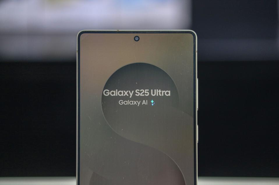 A close-up of the top of a Samsung Galaxy S25 Ultra, showing its small, center-aligned punch-hole selfie camera on the lit screen.