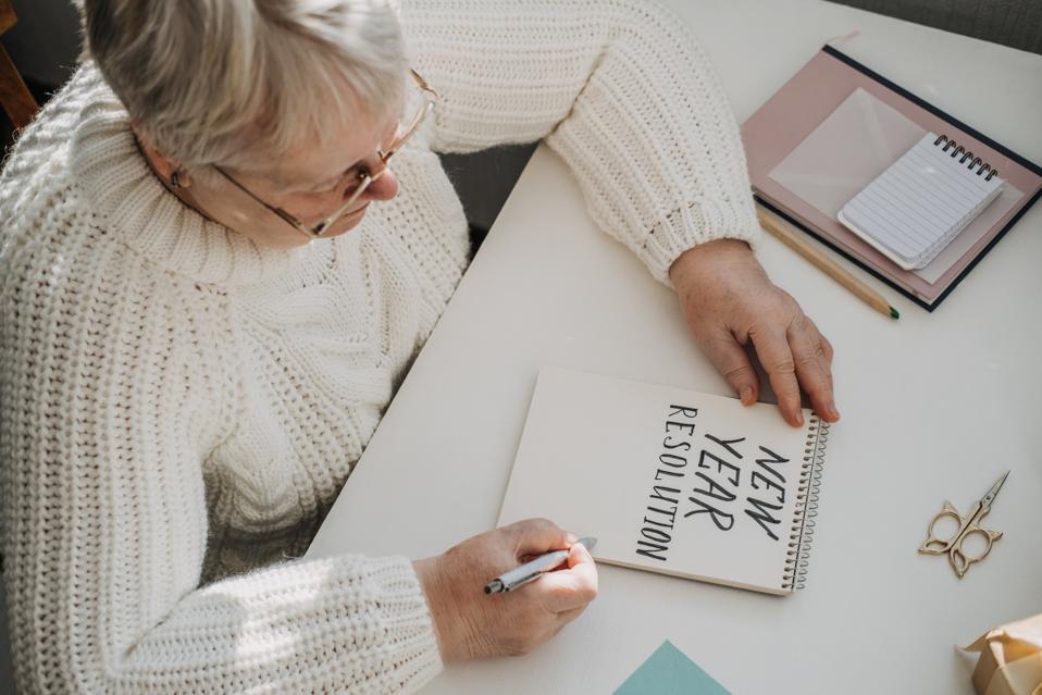 Woman in retirement writing on New Year resolution card