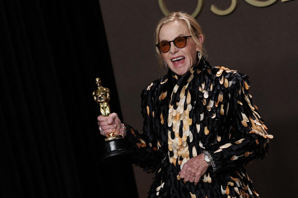 Amy Madigan with her Oscar in one hand and an Omega Seamaster Aqua Terra on her left wrist