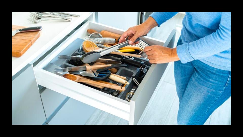 Person taking kitchen tongs out of a cluttered drawer in the kitchen