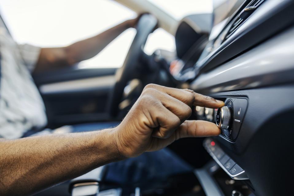 Close up of black driver's hand turning up radio in a car.
