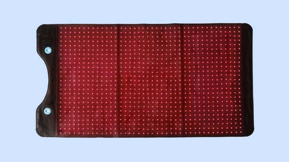 The HIgherDose red light therapy mat against a blue background.