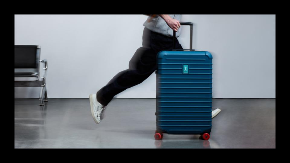 Someone rolling the Cotopaxi Coraza Medium-Checked Suitcase in Blue Spruce.