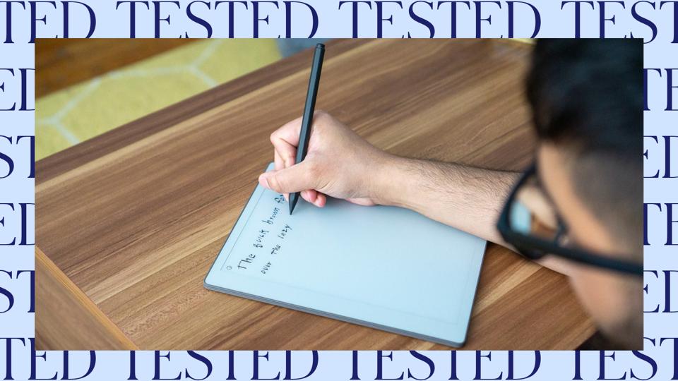 A person in glasses writing on an E Ink writing tablet