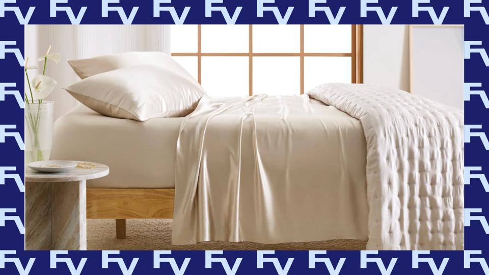 Quince Mulberry Silk Sheet Set in champagne made up on a bed in a room with a window.