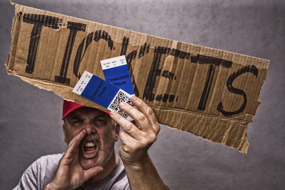 A shady character scalping a pair of concert tickets, yelling while holding a cardboard sign and wearing a red baseball hat. The concert tickets have a QR Code on them.