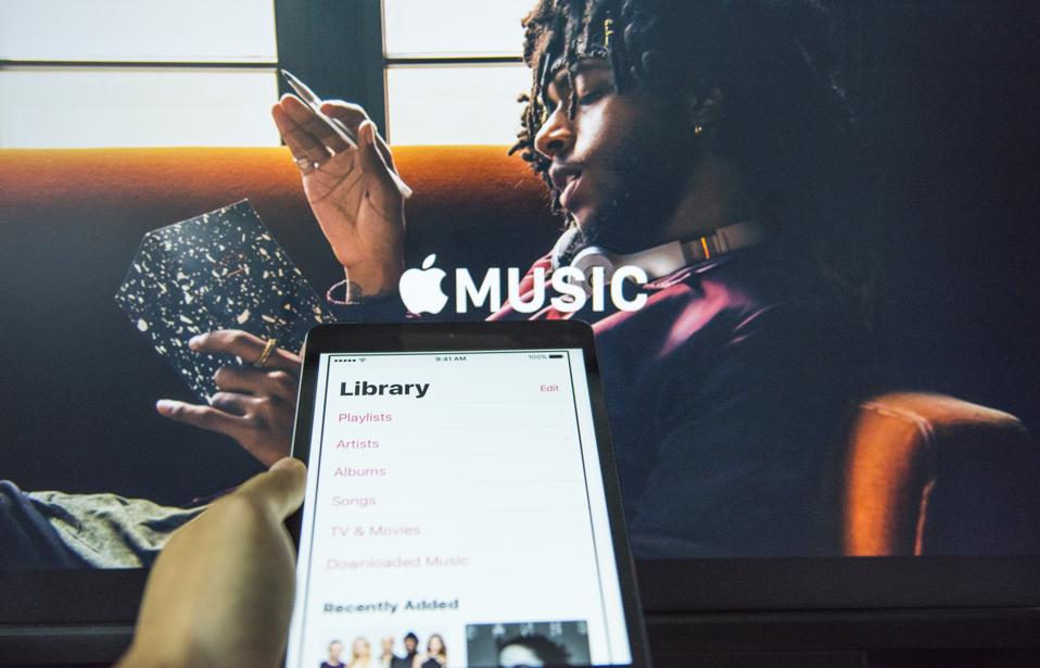 Young man holds a smart device while using Apple Music app.