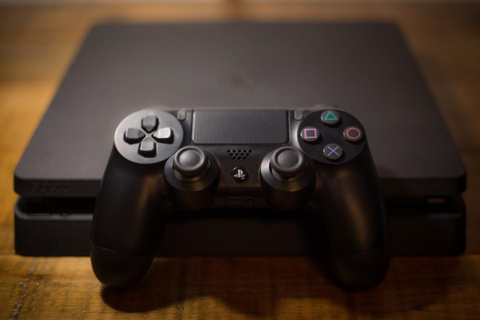 A Sony PlayStation 4 video game console with a black...