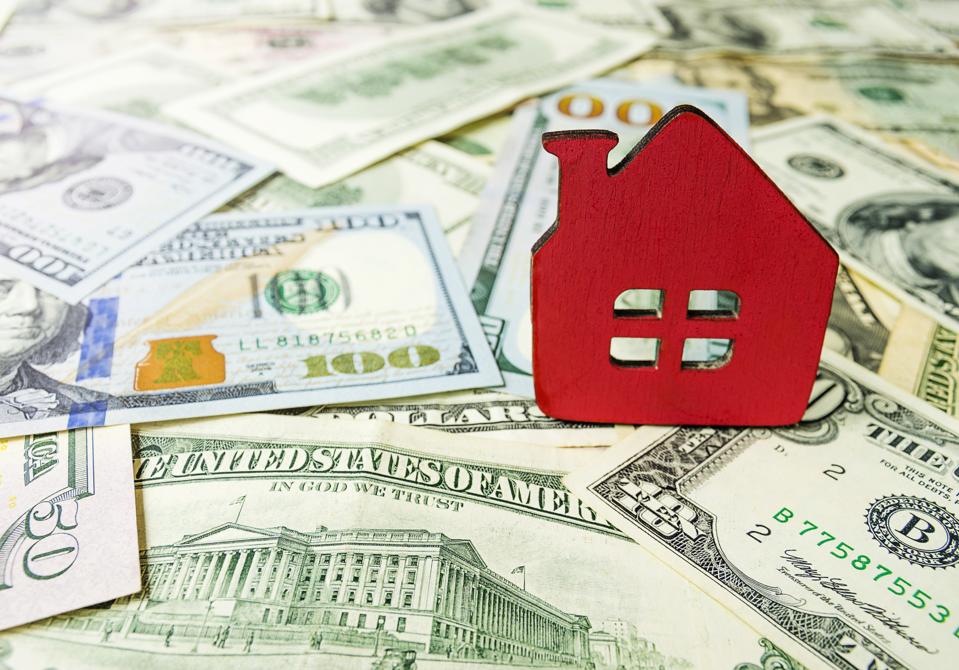 Wooden model house on the background of U.S. dollar bills. Symbolic image of buying or renting a house. Selective focus, copy-space.