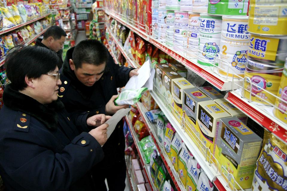 Three Chinese people in supermarket aisle, inspecting packages