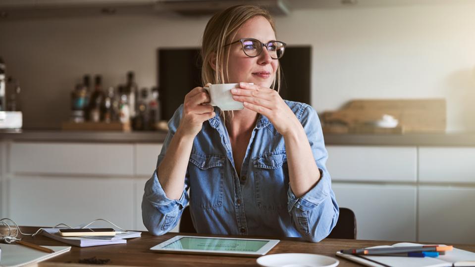 Smiliing woman drinking coffee while working online from home