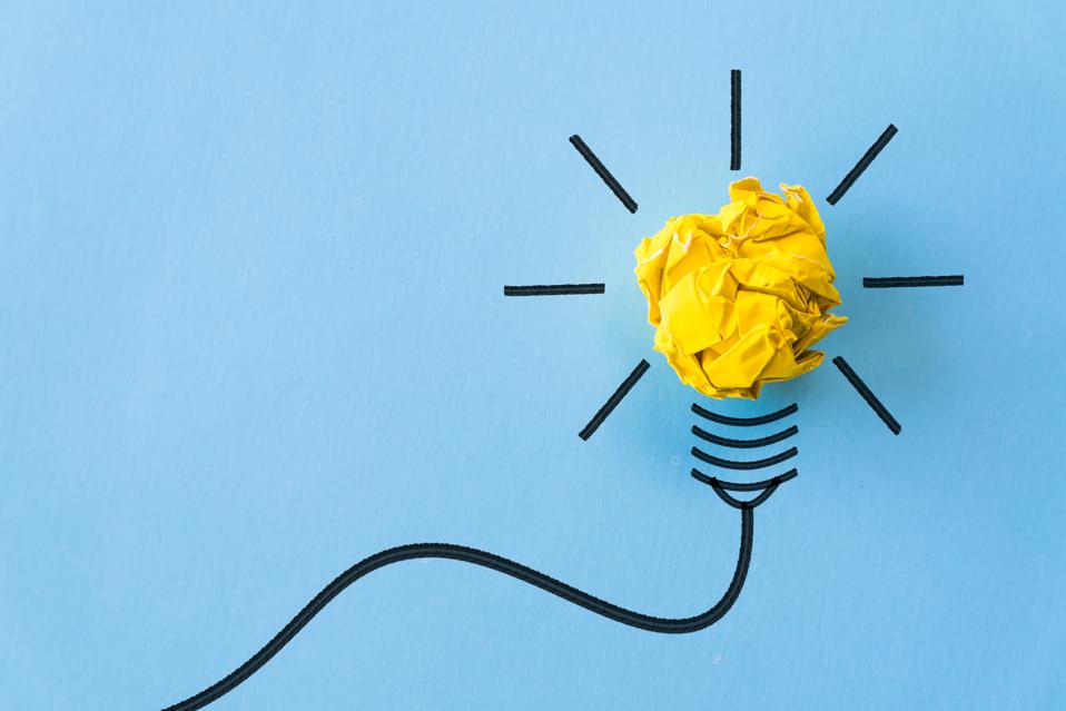 Inspiration and great idea concept. light bulb with crumpled yellow paper on blue background.