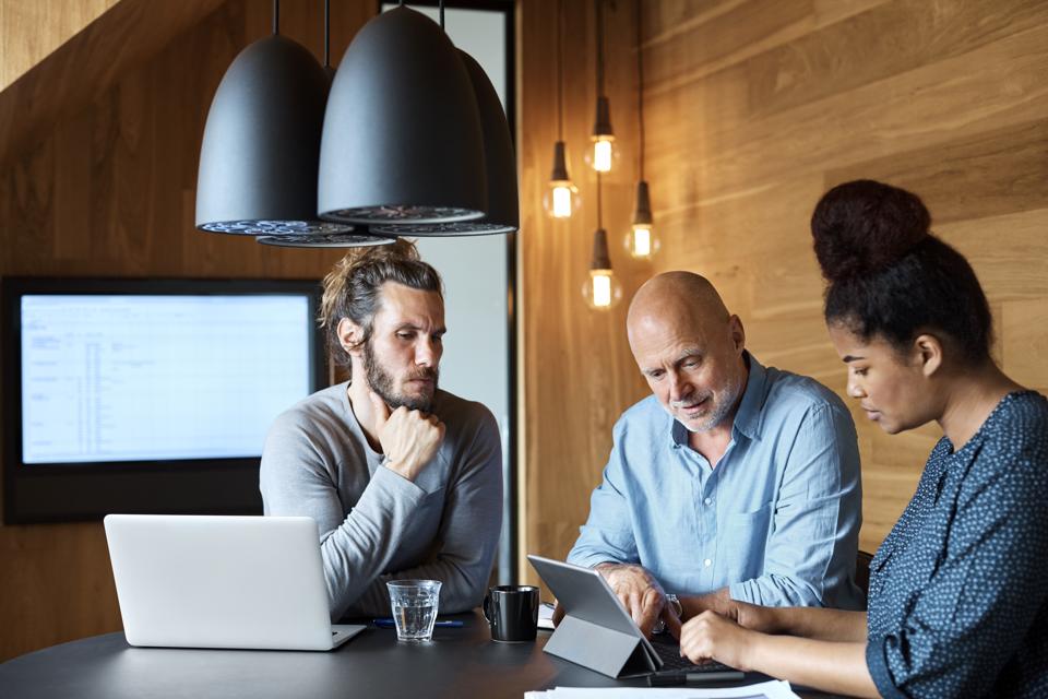 Businessman explaining coworkers through tablet pc