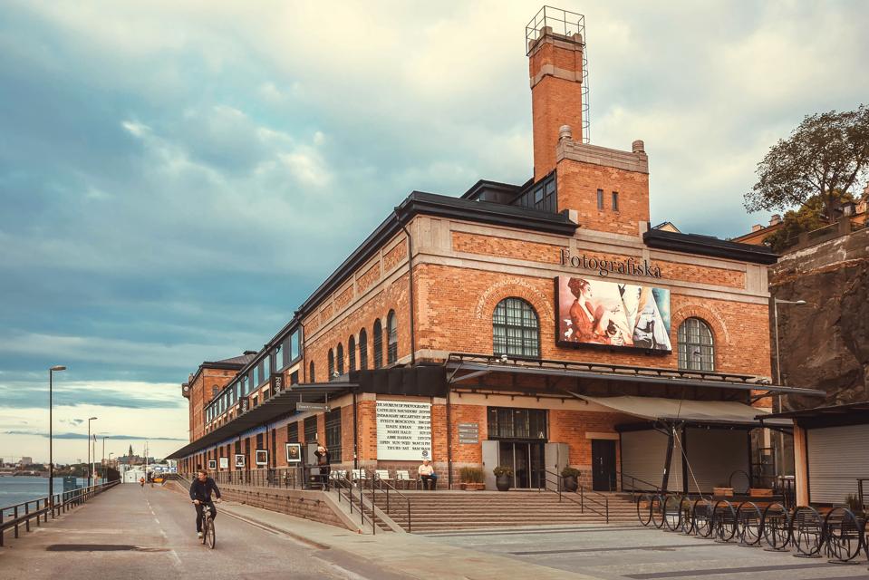 Cyclist driving past bilding of the cultural center Fotografiska with brick walls