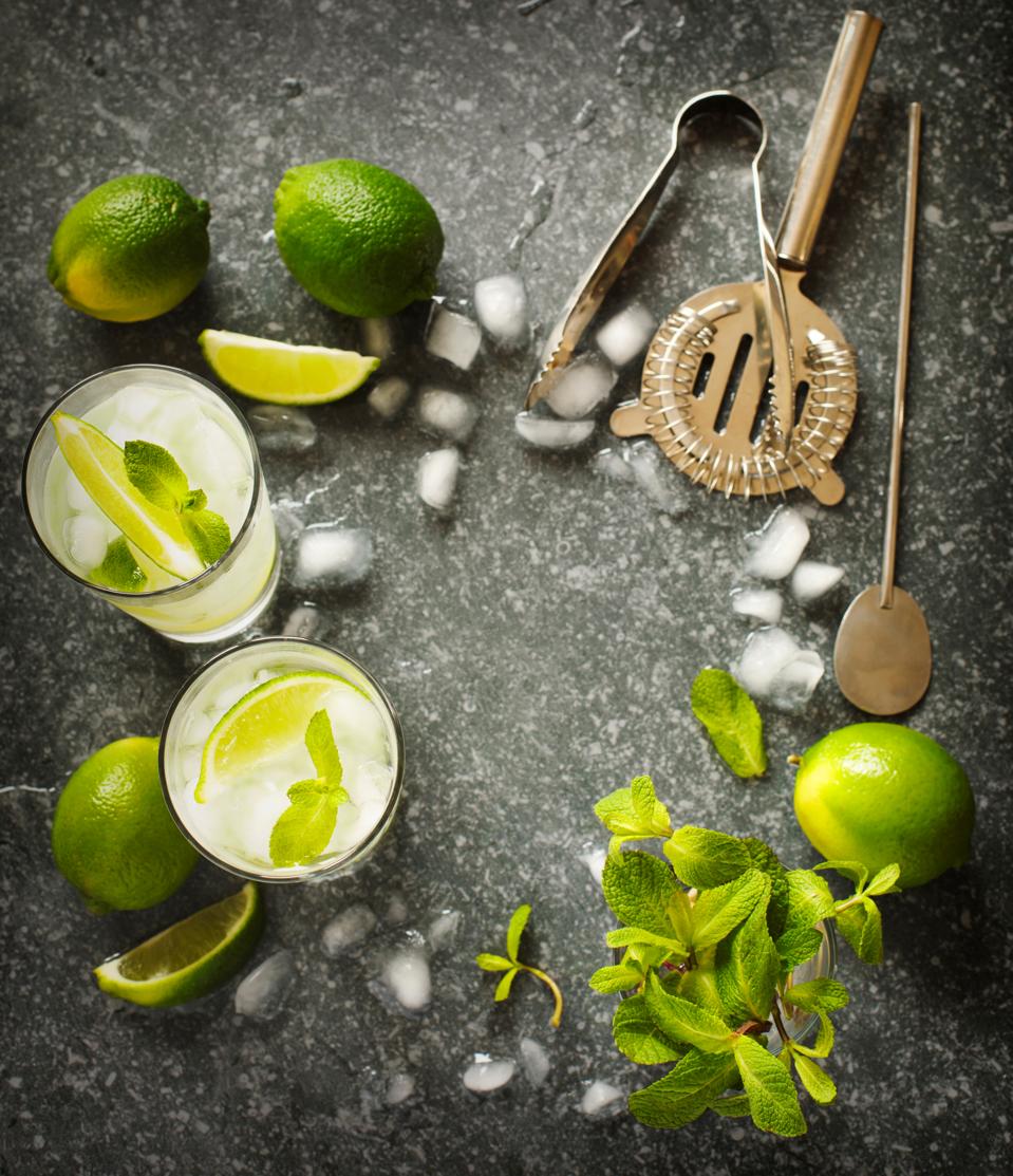 Mojito cocktail with lime and mint in glass on a stone table. Bar tools and ingredients for cocktail.